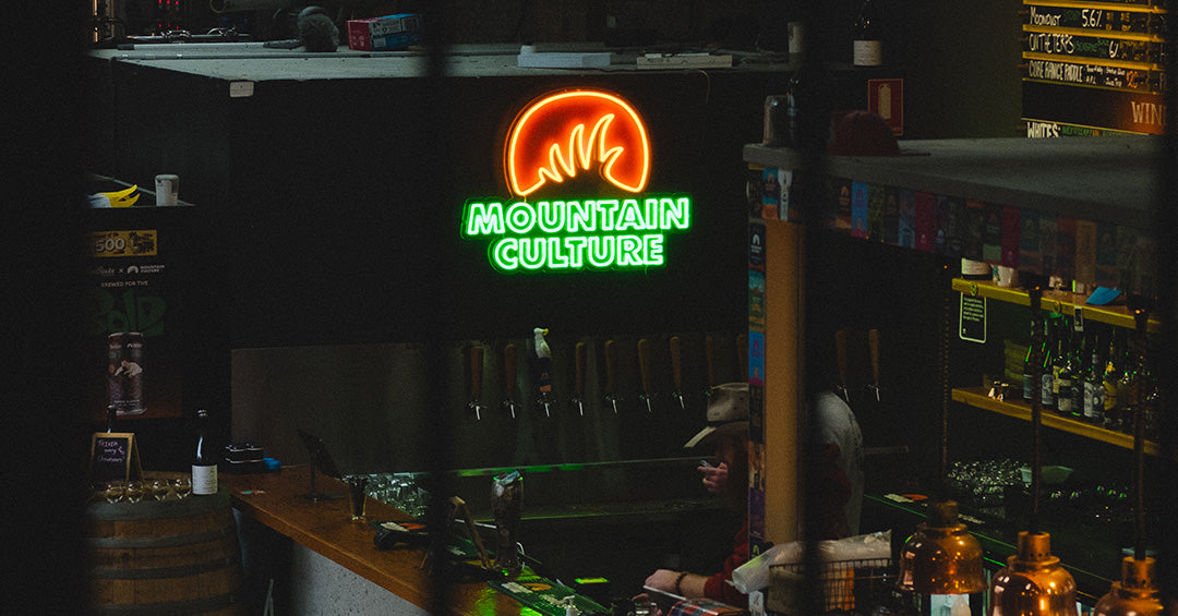 Mountain Culture neon logo above the bar taps